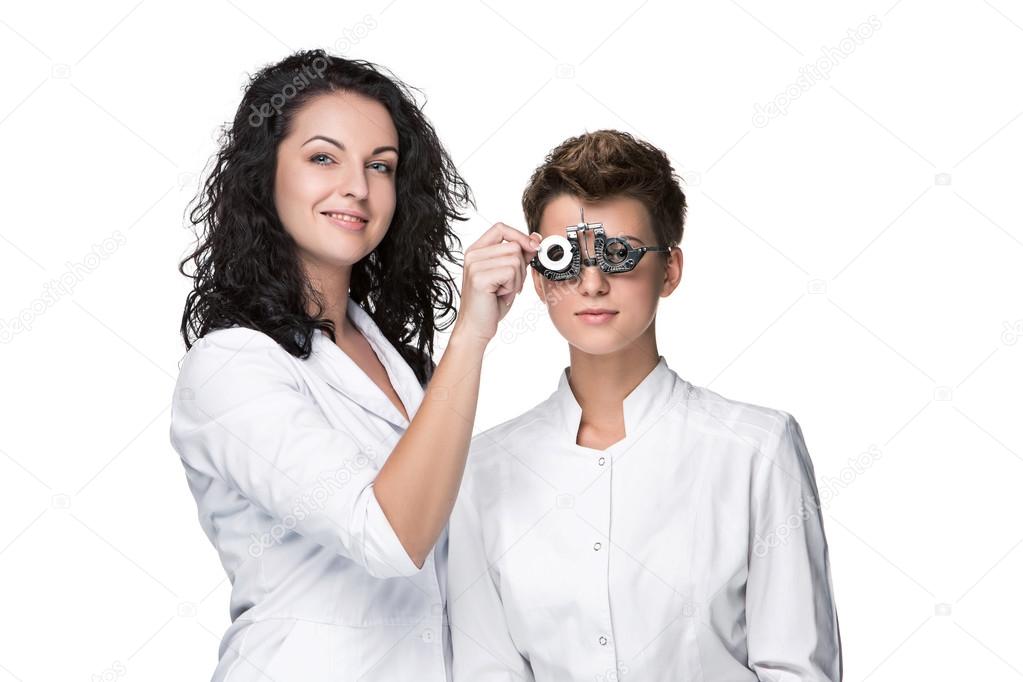 Optometrist holding an eye test glasses and giving to young woman examination