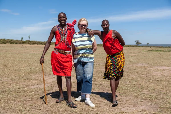 MASAI MARA, KENIA, AFRICA- 12 FEB Masai hombres en ropa tradicional y turistas europeos, revisión de la vida cotidiana de la población local, cerca de la Reserva del Parque Nacional Masai Mara, Feb 12, 2010, Kenia — Foto de Stock