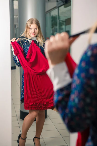 Mulher tentando vermelho vestido de compras para roupas . — Fotografia de Stock