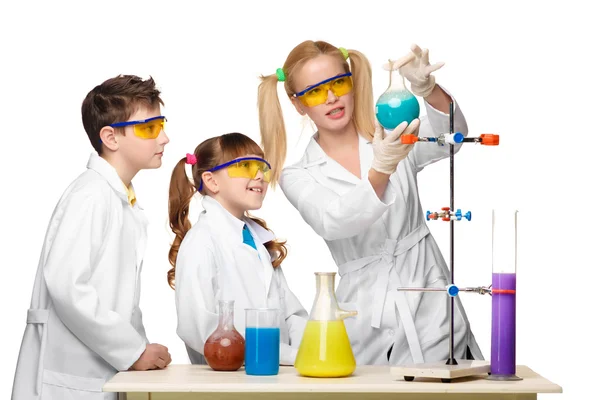 Teens and teacher of chemistry at  lesson making experiments — Stock Photo, Image