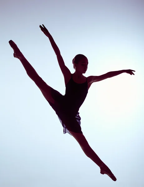 Schöne junge Balletttänzerin springt auf einem grauen Hintergrund. — Stockfoto