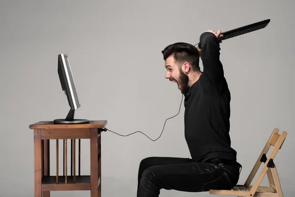 Homem irritado está destruindo um teclado — Fotografia de Stock