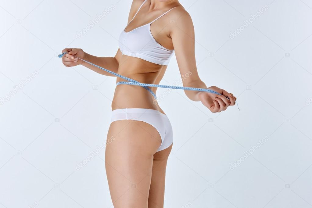 Woman holding meter measuring perfect shape of her beautiful body 