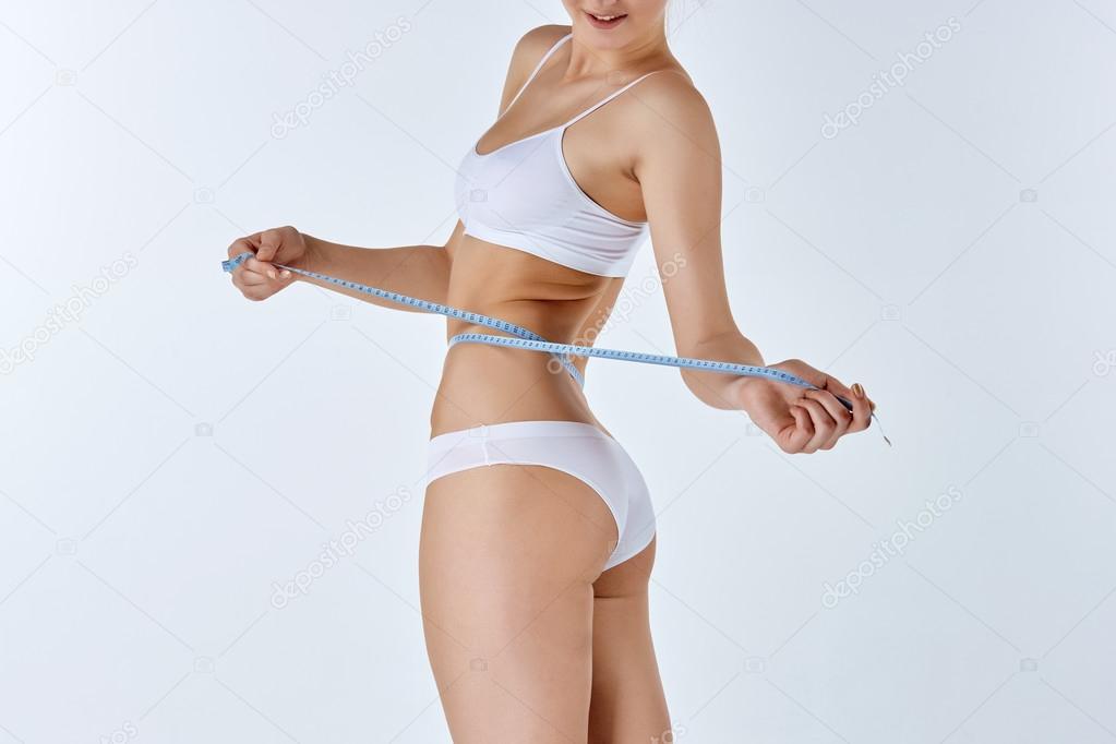 Woman holding meter measuring perfect shape of her beautiful body 