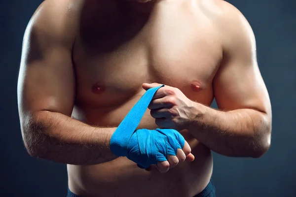 Muscular boxer bandaging suas mãos no fundo cinza — Fotografia de Stock