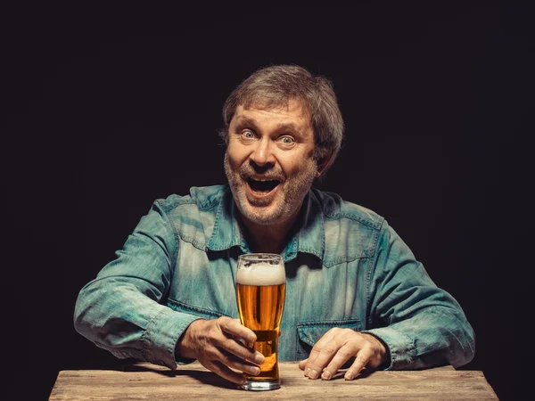 El hombre sonriente en camisa de mezclilla con vaso de cerveza —  Fotos de Stock