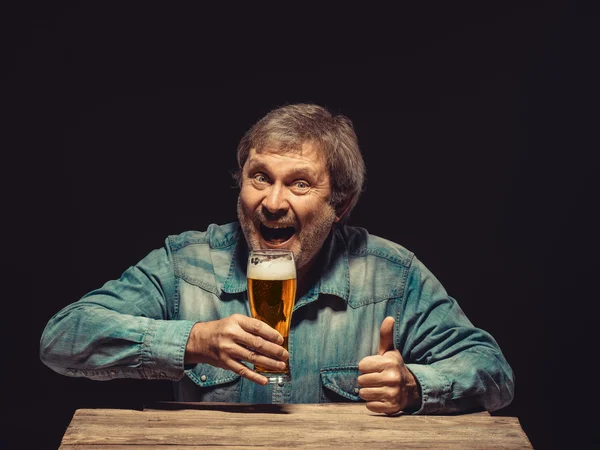 El hombre sonriente en camisa de mezclilla con vaso de cerveza —  Fotos de Stock