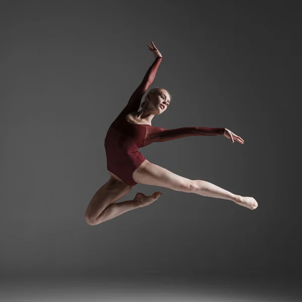 Молодая красивая танцовщица в современном стиле, прыгающая на фоне студии — стоковое фото
