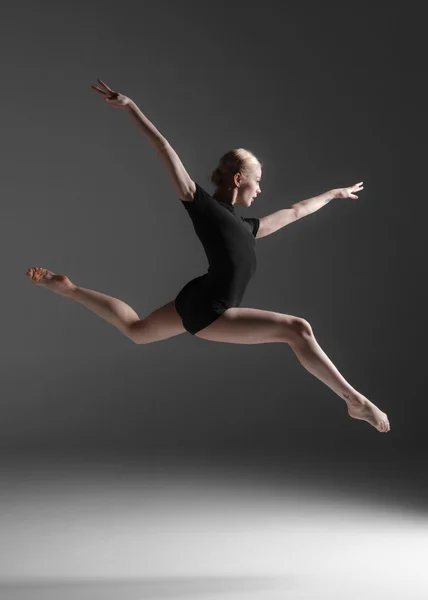 Junge schöne moderne Tänzerin springt auf einem Studiohintergrund — Stockfoto