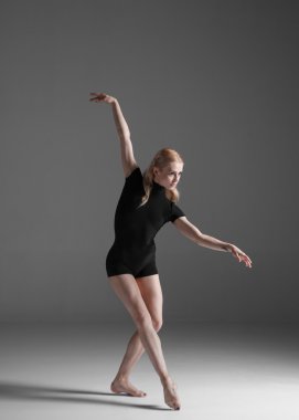 Stüdyo arka planında poz veren genç, güzel modern bir dansçı.