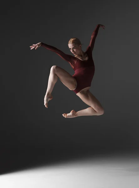 Junge schöne moderne Tänzerin springt auf einem Studiohintergrund — Stockfoto