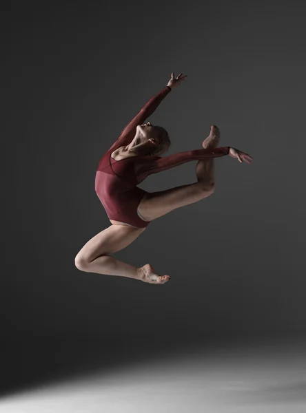 Young beautiful modern style dancer jumping on a studio background — Stock Photo, Image