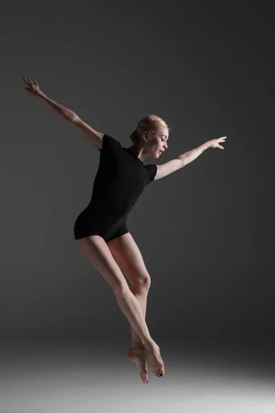 Joven hermosa bailarina de estilo moderno saltando sobre un fondo de estudio — Foto de Stock