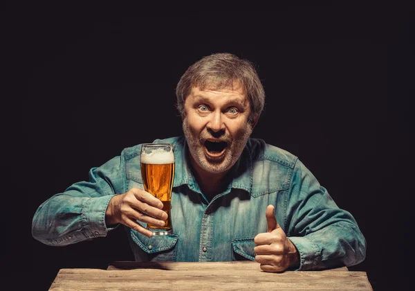 Den leende mannen i jeansskjorta med glas öl — Stockfoto