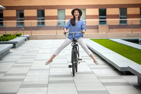 Mooi meisje in hoed een fiets op straat — Stockfoto