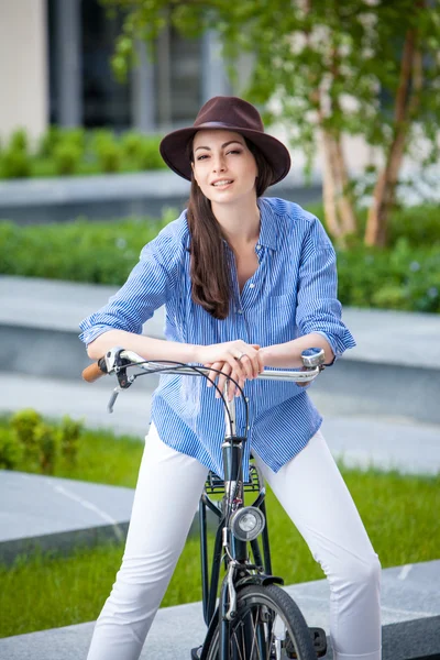 Mooi meisje in hoed een fiets op straat — Stockfoto