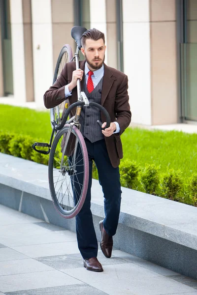 Bonito homem de negócios carregando sua bicicleta — Fotografia de Stock