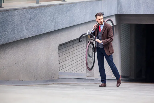 Beau homme d'affaires portant son vélo — Photo