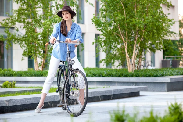 Mooi meisje in hoed een fiets op straat — Stockfoto