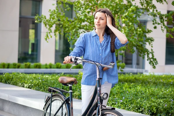 Menina bonita com uma bicicleta na estrada — Fotografia de Stock