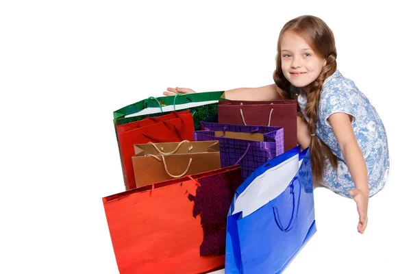Menina feliz com sacos de compras sentado no estúdio — Fotografia de Stock