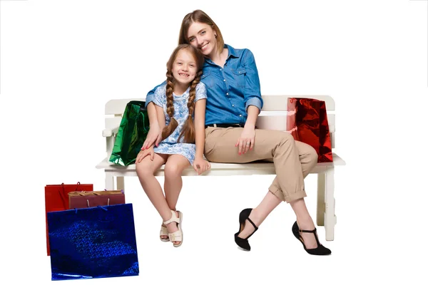 Счастливые мать и дочь с сумками для покупок сидят в студии — стоковое фото