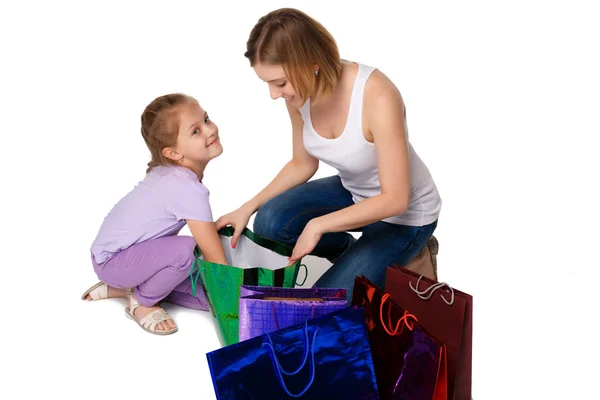 Feliz madre e hija con bolsas de compras sentadas en el estudio —  Fotos de Stock