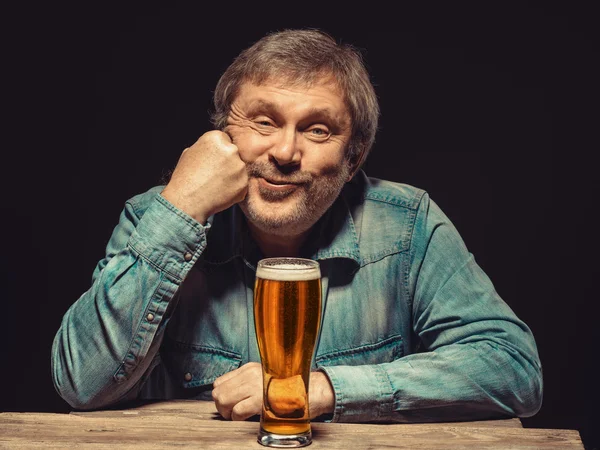 Der zufriedene Mann im Jeanshemd mit einem Glas Bier — Stockfoto