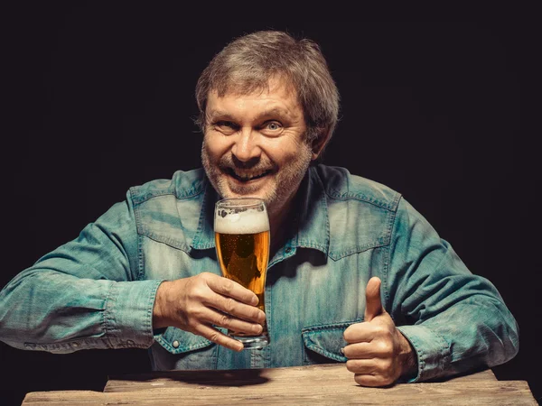 Den leende mannen i jeansskjorta med glas öl — Stockfoto