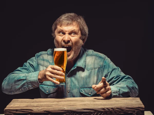 The screaming man in denim shirt with glass of beer