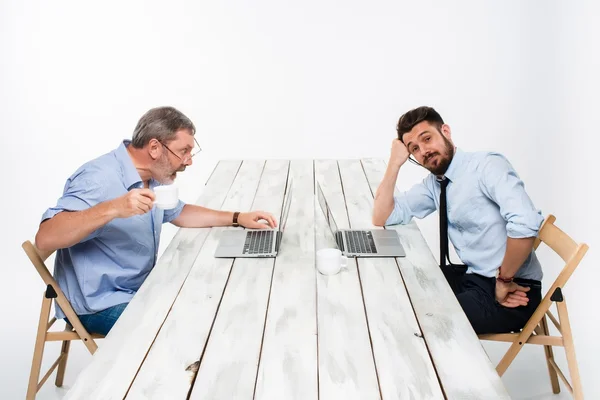 Los dos colegas trabajando juntos en la oficina sobre fondo gris —  Fotos de Stock