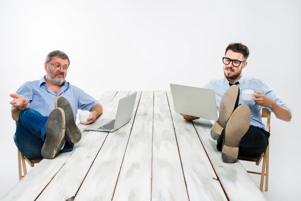 The two businessmen with legs over table working on laptops — Stock Photo, Image