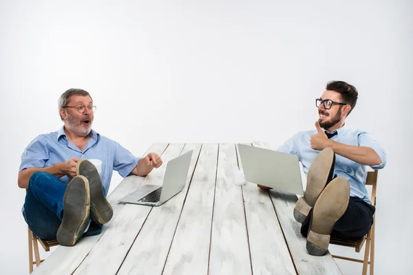 Die beiden Geschäftsleute mit Beinen über dem Tisch, die an Laptops arbeiten — Stockfoto