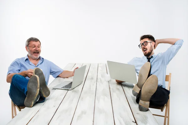 Los dos hombres de negocios con las piernas sobre la mesa trabajando en computadoras portátiles —  Fotos de Stock