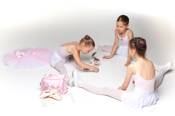Три маленькие балетные девочки сидят и позируют вместе
