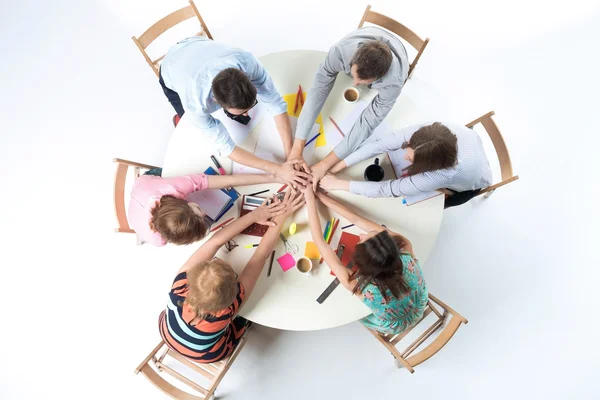 Vista dall'alto. Mani unite del team aziendale sullo sfondo dello spazio di lavoro — Foto Stock