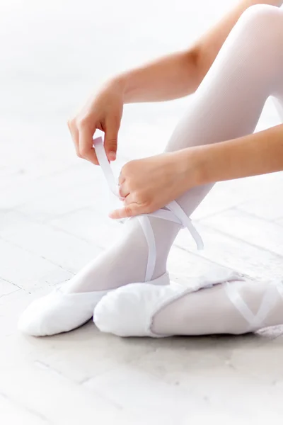 Little ballerina puting on foot pointe shoes — Stok fotoğraf