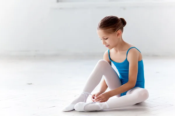 Vackra lilla ballerina i blå klänning för Dans sätter på foten pointe skor — Stockfoto