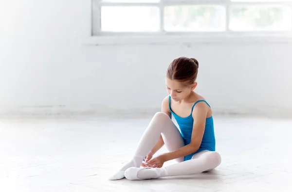 Vackra lilla ballerina i blå klänning för Dans sätter på foten pointe skor — Stockfoto