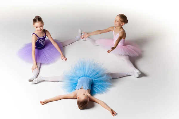 Tres pequeñas chicas de ballet sentadas en tutú y posando juntas — Foto de Stock