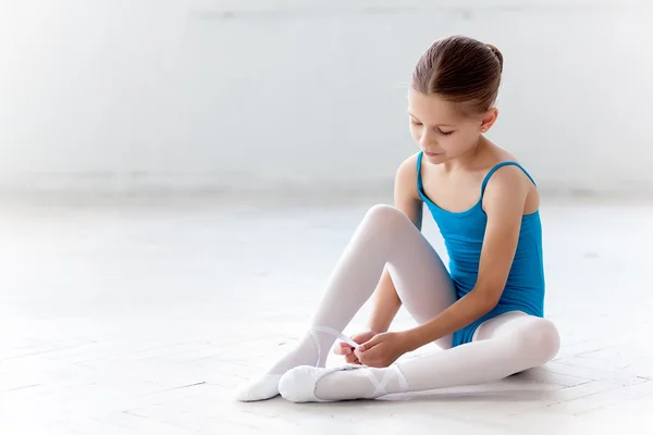 Hermosa pequeña bailarina en vestido azul para bailar puting en zapatos de punta de pie — Foto de Stock