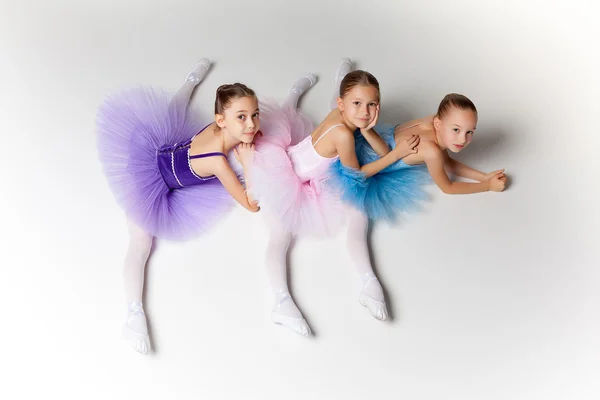 Tres pequeñas chicas de ballet sentadas en tutú y posando juntas —  Fotos de Stock