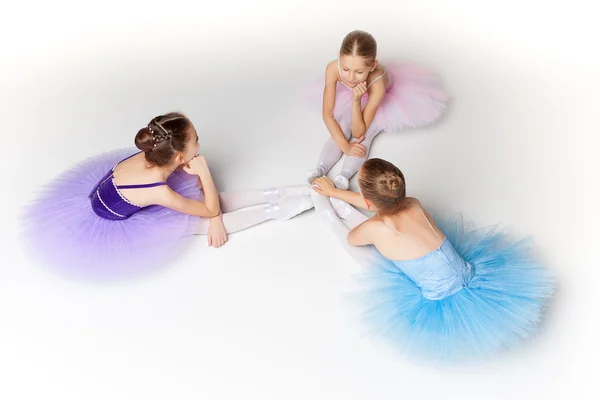 Tres pequeñas chicas de ballet sentadas en tutú y posando juntas —  Fotos de Stock