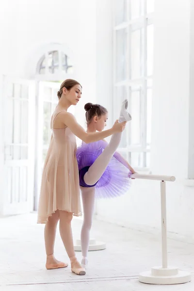 La pequeña bailarina posando en la barra de ballet con su profesora personal en el estudio de danza — Foto de Stock