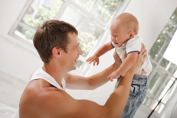 Young father with his nine months old son on the bed at home — Stock Photo, Image