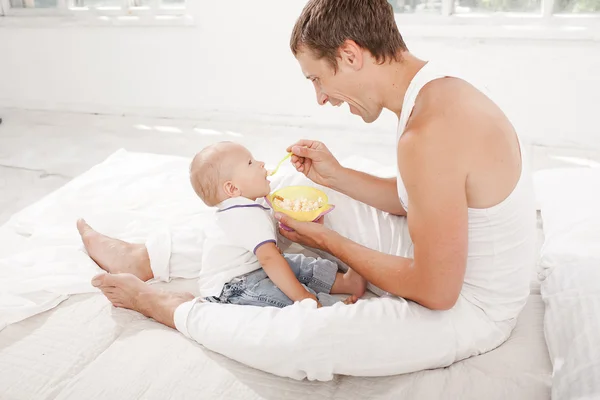 Young father with his nine months old son on the bed at home — Stock Photo, Image