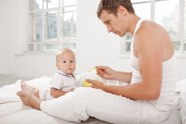 Young father with his nine months old son on the bed at home