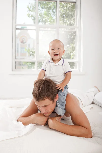 Young father with his nine months old son on the bed at home — Stock Photo, Image