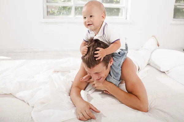 Молодий батько з дев'ятимісячним сином на ліжку вдома — стокове фото