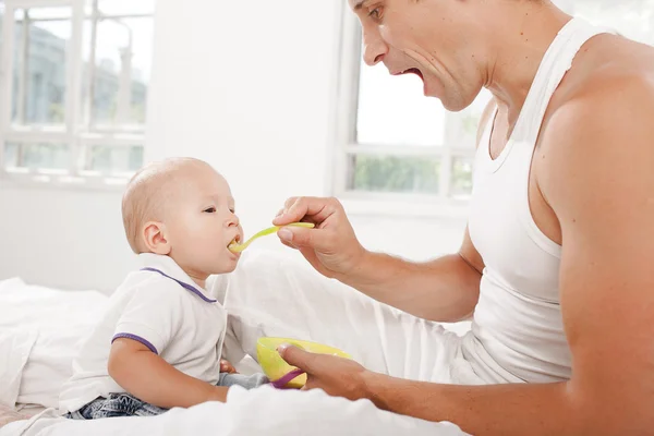 Young father with his nine months old son on the bed at home